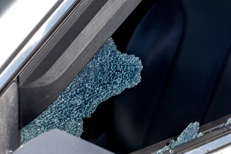 Vitres latérales d'une voiture brisées avec des éclats de verre visibles, semblant provoquer des dommages au pare-brise à Lorient