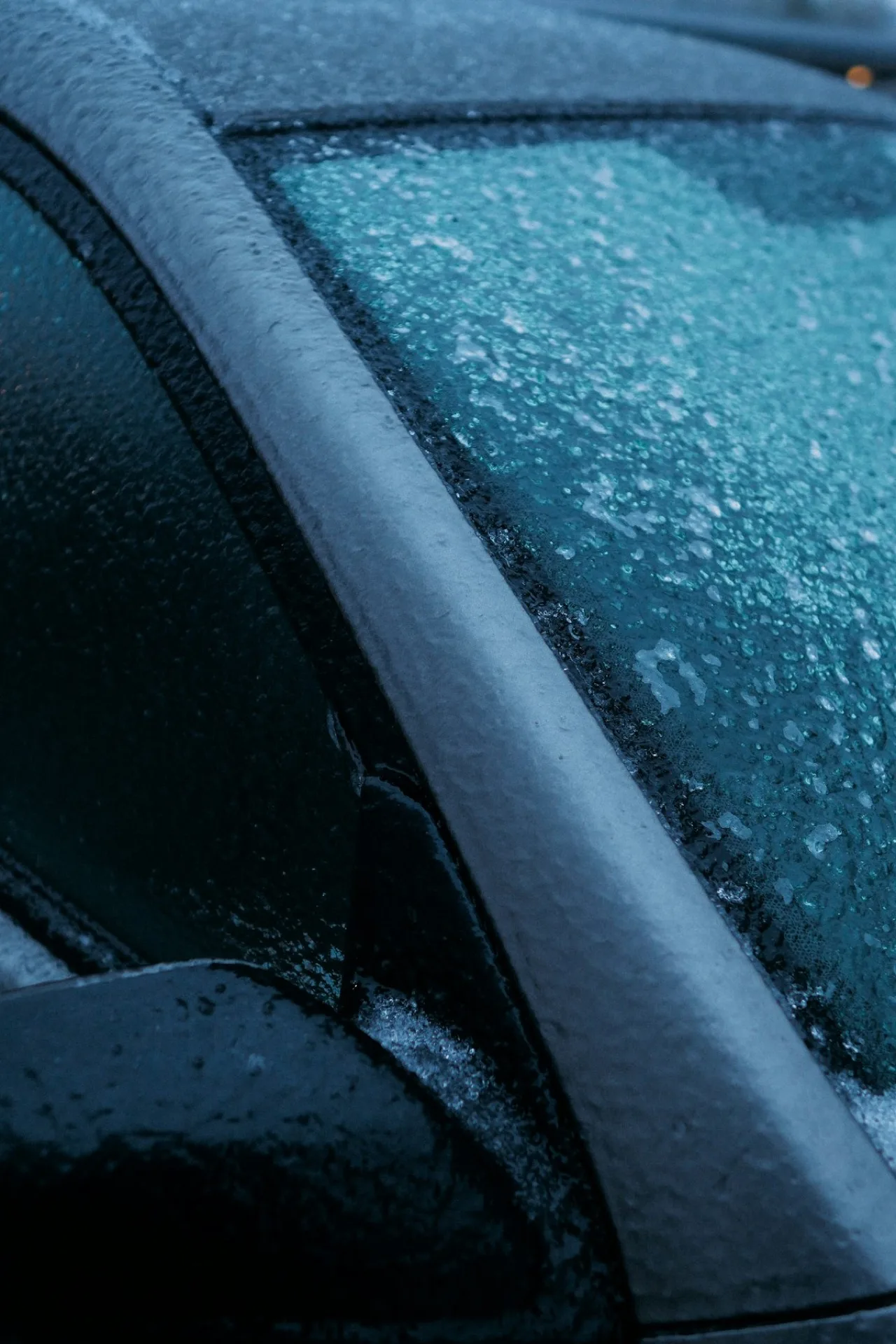 Pare-brise de voiture couvert de givre au petit matin, montant et essuie-glace visibles