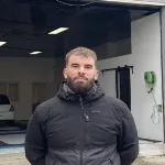 Homme debout devant un atelier de réparation automobile à Lorient spécialisé dans le remplacement de pare-brise